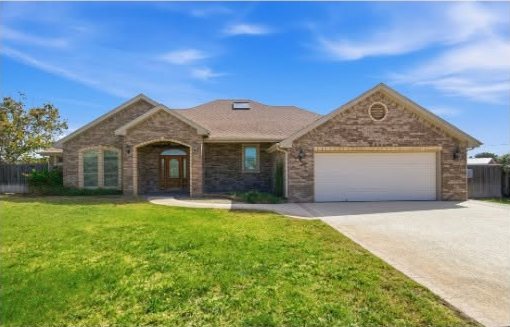 Brick home with green lawn and wide driveway