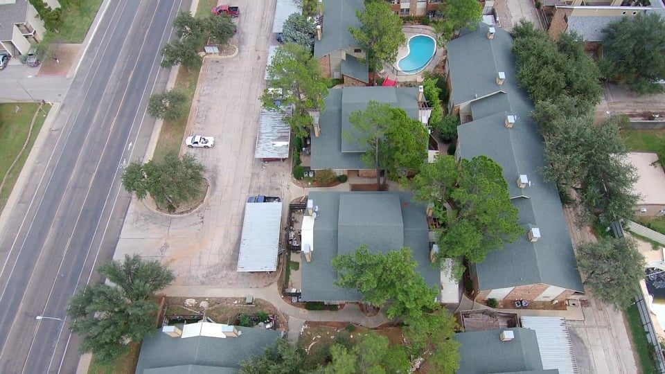 Aerial view of a neighborhood with trees and a pool